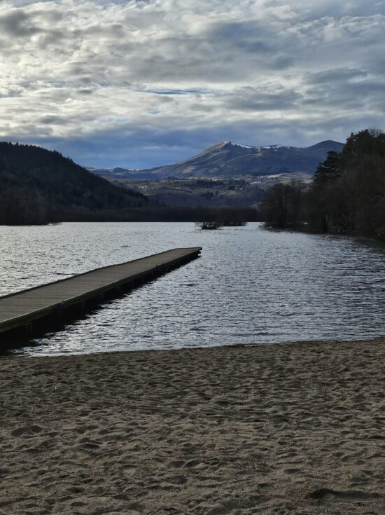 Plage du Lac Chambon entourée de volcans, lieu de détente prisé en été en Auvergne.